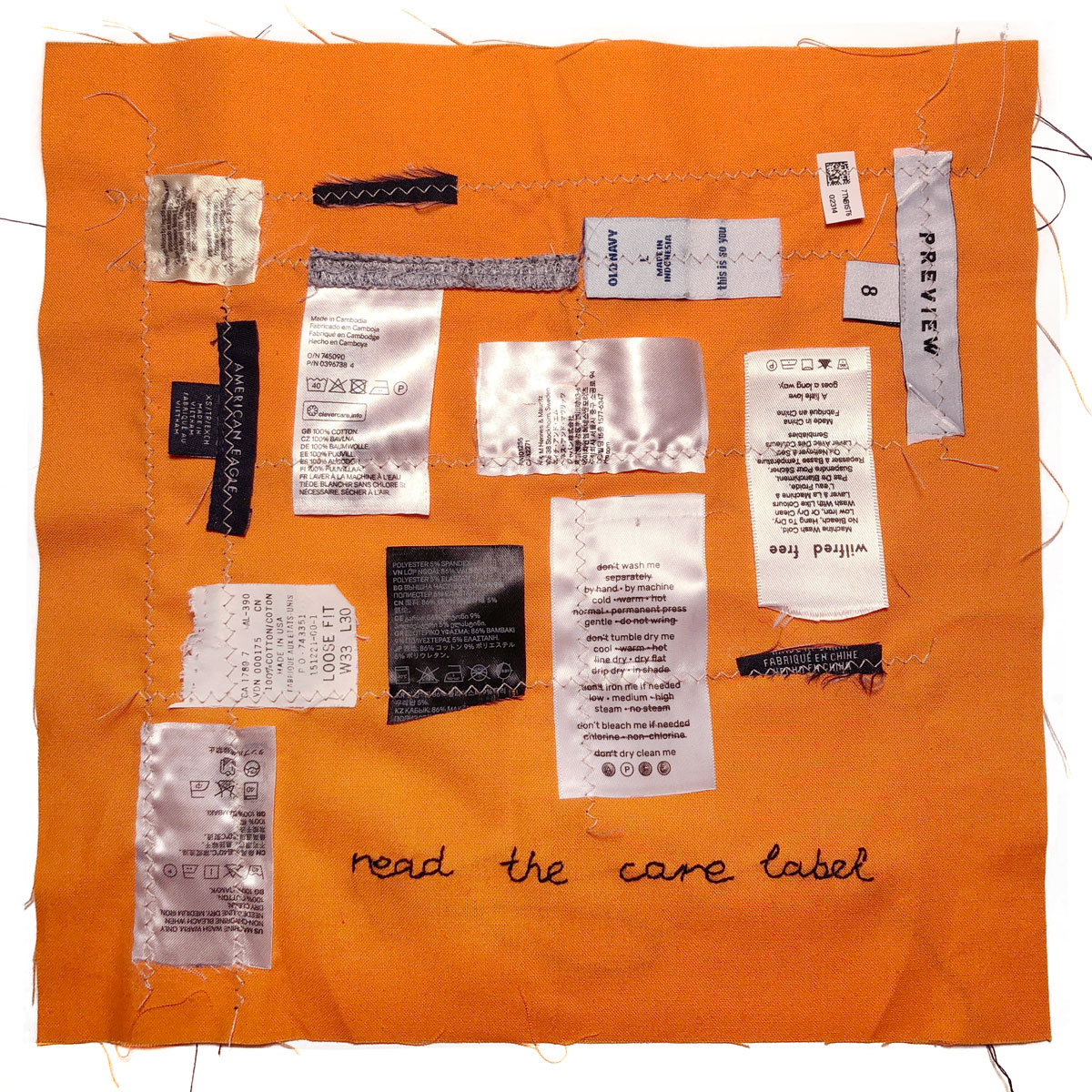 A hand square of fabric with clothing labels and the text 'Read the care label' sewn into the design. Part of the Textile Upcycling Manifesto by Liz Broekhuyse