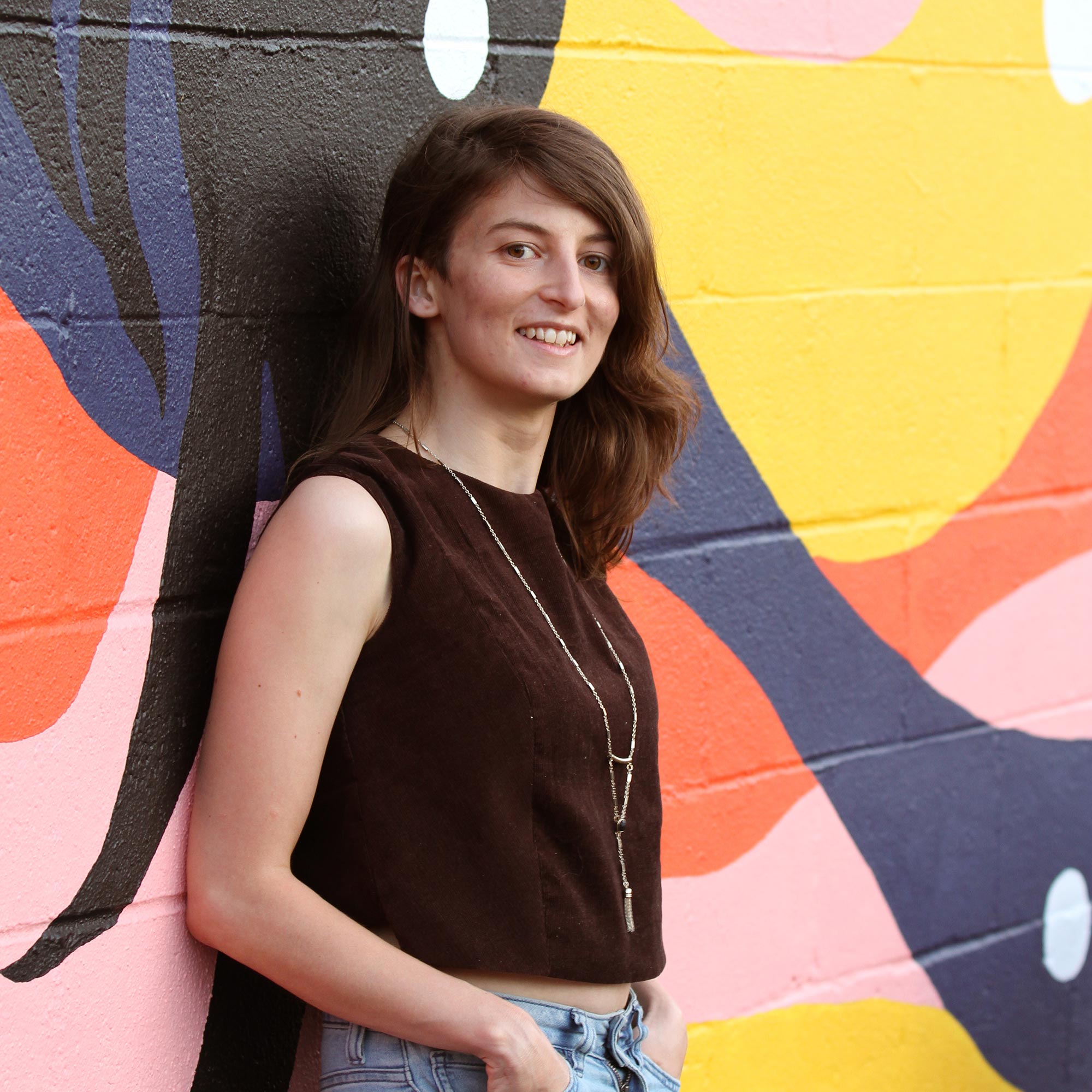 Photo of Liz Broekhuyse standing in front of a brightly painted mural